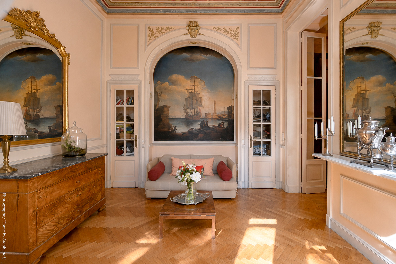 Petit salon orné de grandes toiles marines et miroirs dorés
